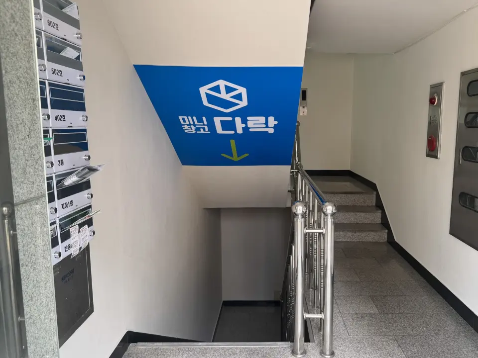 1층 로비에서 지하 1층으로 내려가는 계단과 다락 안내 사인